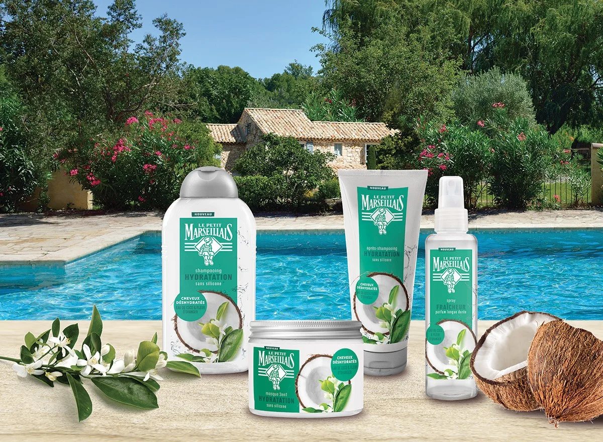 The Le Petit Marseillais Coco range arranged in its retail scene: the full product family grouped with coconuts and orange blossom