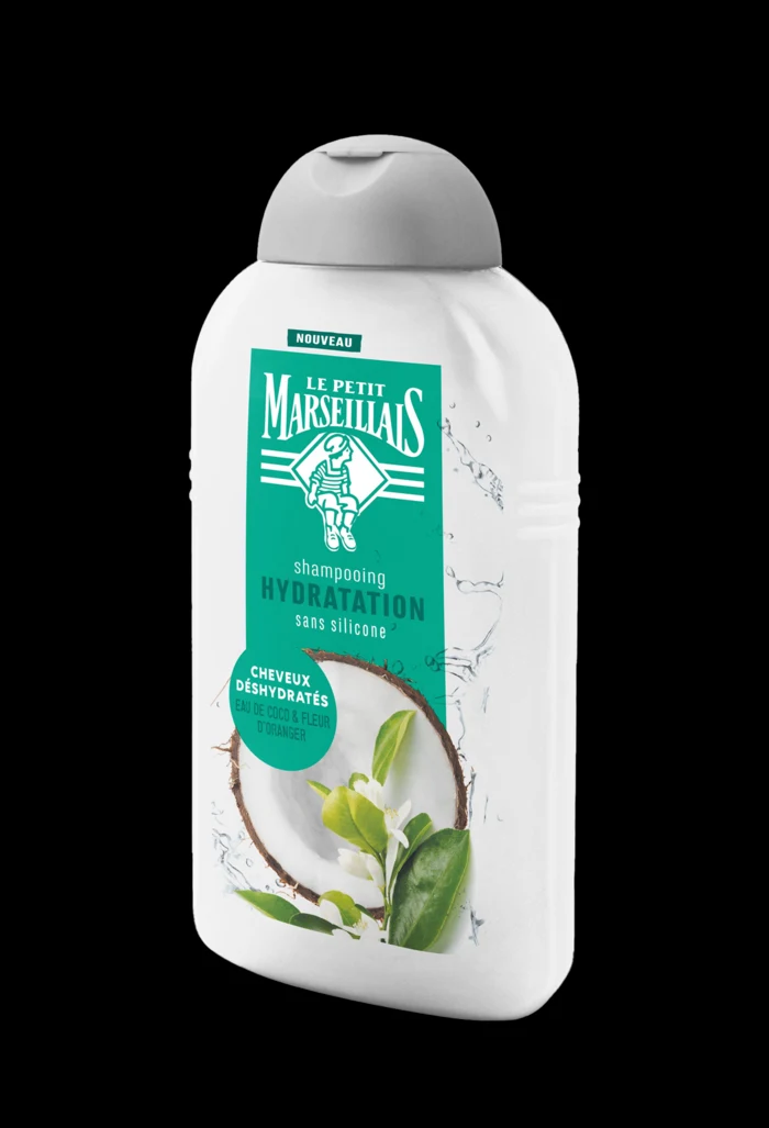 Le Petit Marseillais Hydratation shampoo bottle with the reworked coconut and orange blossom label, standing against a black ground