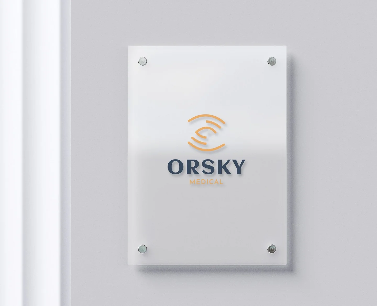 The ORSKY Medical identity in place: the gold eye mark and navy wordmark on the frosted glass entrance sign of the ultrasound clinic